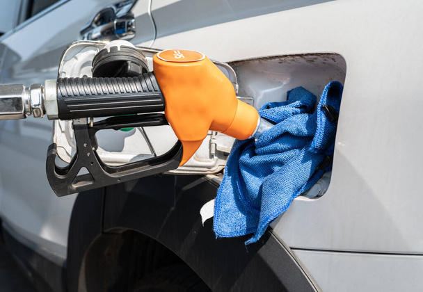 Апельсинова сопло під час заправки бензину до паливного бака автомобіля на АЗС. АЗС це об'єкт, який продає паливо та мастила для автомобілів
. - Фото, зображення