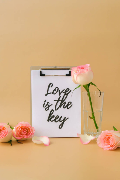 LOVE IS THE KEY text on greeting card paper note. Delicate pink roses on beige background. Minimal trendy composition. Romantic pastel pink rose flowers. Neutral earth tones. Valentines Mothers Womens - Fotografie, Obrázek