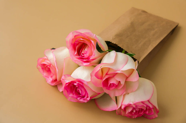 Delicadas rosas rosadas en bolsa de papel artesanal sobre fondo beige. Composición de moda mínima. Idea de arte abstracto. Románticas flores rosadas pastel. Estética moderna. Tonos neutros de tierra Banner - Foto, imagen