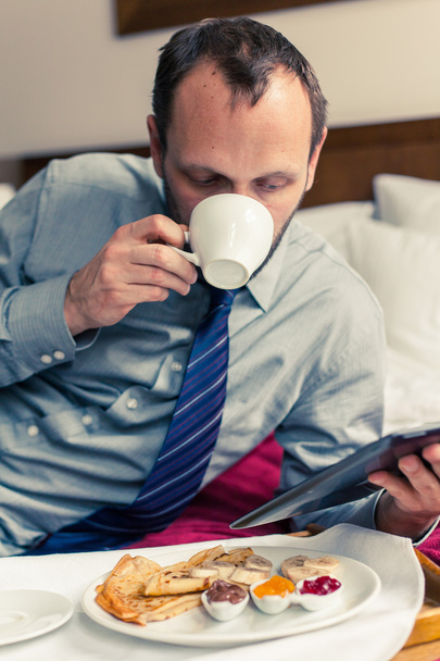 Businessman working on tablet during breakfast - Photo, image