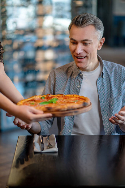 A man eating pizza and looking excited - Foto, immagini