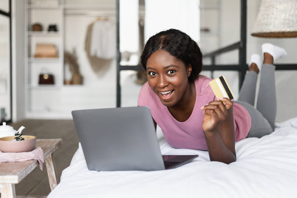 Femme noire montrant des achats par carte de crédit sur ordinateur portable à la maison - Photo, image