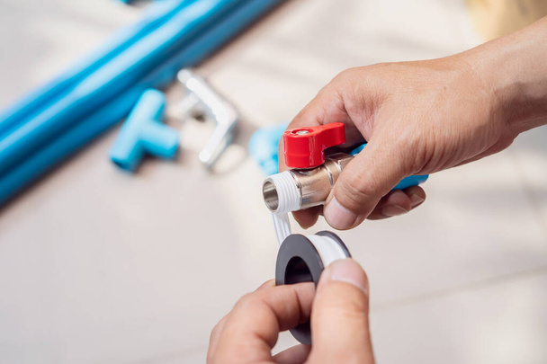 Klempner legt Teflon-Fadenband auf den Faden, Vorbereitung auf den Anschluss an PVC-Rohr zu Hause , - Foto, Bild