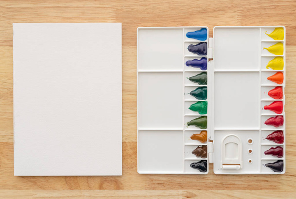 Aquarellfarben in weißer Palette mit weißem Papier als Hintergrund. Bunte Aquarellfarben im Malkasten. - Foto, Bild
