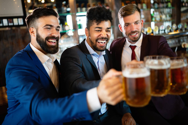 Business men fans screaming and watching football on TV and drink beer in a pub - 写真・画像