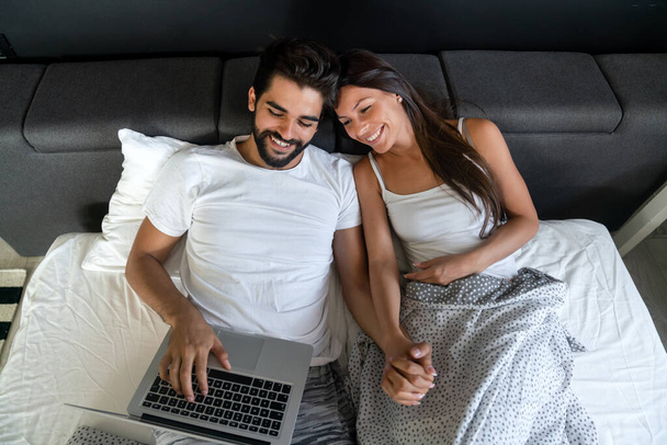 Happy young couple relaxing at home with laptop. Love, happiness, people and fun concept. - Foto, Bild