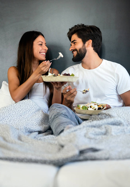 Romantic happy couple having breakfast in bed at home - Photo, Image