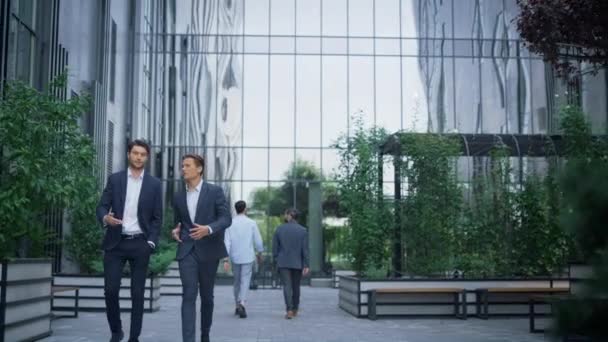 Dos exitosos hombres de negocios caminando en el moderno edificio de oficinas discutiendo proyecto. - Metraje, vídeo