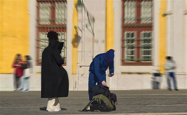 Ένας άντρας και μια γυναίκα στο πεζοδρόμιο με ένα σακίδιο. - Φωτογραφία, εικόνα