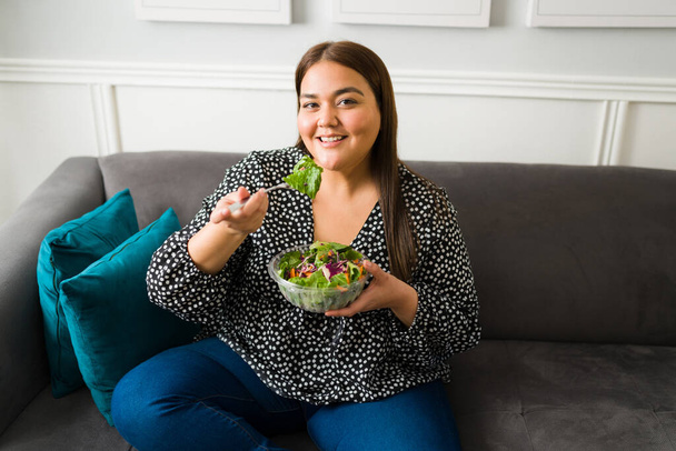 Hermosa mujer latina comiendo una ensalada verde saludable. Mujer joven gorda en una dieta tratando de perder peso - Foto, imagen