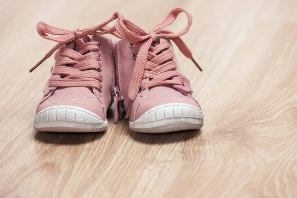 paar roze baby schoenen op de vloer - Foto, afbeelding