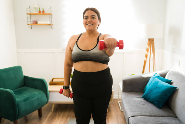 Retrato de uma mulher gorda feliz levantando pesos e animado para o seu progresso em seus objetivos de perda de peso - Foto, Imagem