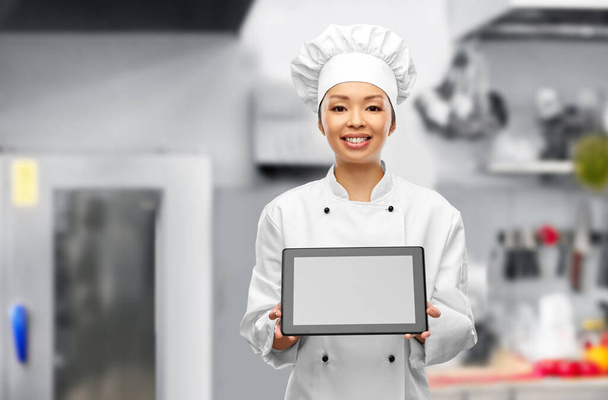 smiling female chef showing tablet pc in kitchen - Foto, Bild