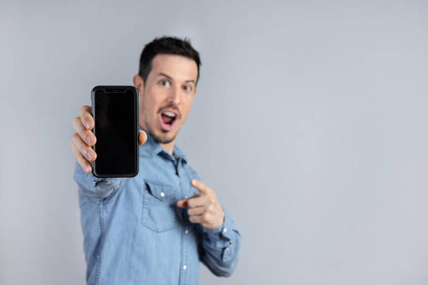 Surprised Man Shows Smart phone screen for mock up - Foto, immagini