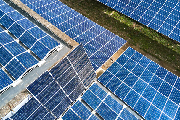 Aerial view of solar power plant with blue photovoltaic panels mounted on industrial building roof for producing green ecological electricity. Production of sustainable energy concept - Photo, Image