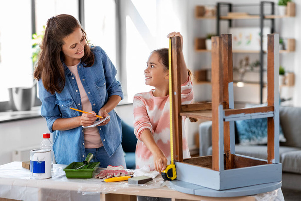 mother and daughter with ruler measuring old table - 写真・画像