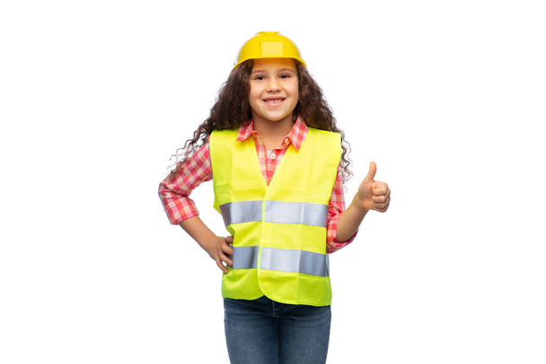 girl in helmet and safety vest shows thumbs up - Foto, immagini
