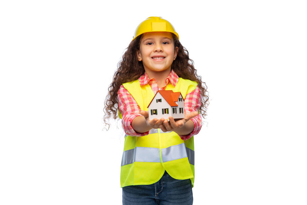 girl in helmet and safety vest holding house - Foto, afbeelding