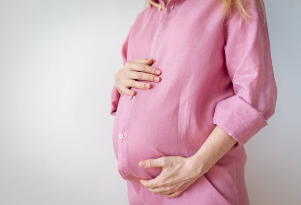 una donna incinta sta con le mani sullo stomaco, il concetto di aspettare un bambino - Foto, immagini