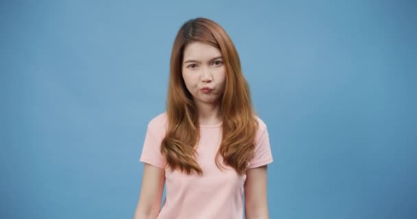 Fiatalság vonzó ázsiai hölgy mosollyal viselni rózsaszín alkalmi kikérdezett fontolja keresztek karok és pontok oldalra választ két lehetőség elszigetelt kék háttérrel. A lány balra és jobbra mutat..  - Felvétel, videó