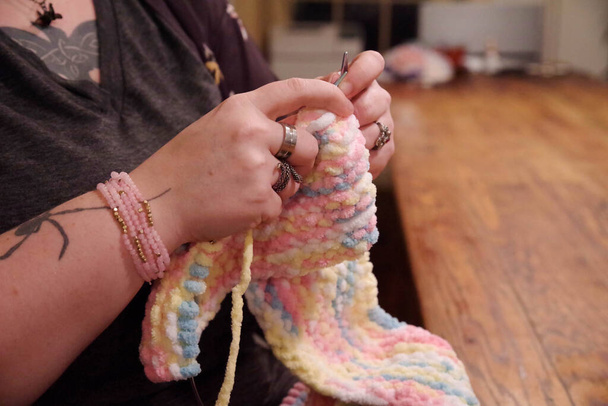 El primer plano de las manos femeninas tejiendo en casa con tatuajes y joyas - Foto, Imagen