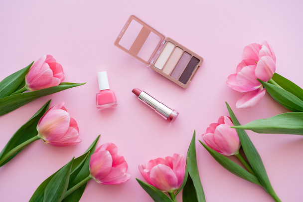 top view of decorative cosmetics near blooming tulips on pink - Photo, Image