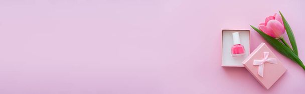 вид зверху лак для нігтів всередині подарункової коробки біля тюльпана на рожевому, банер
 - Фото, зображення