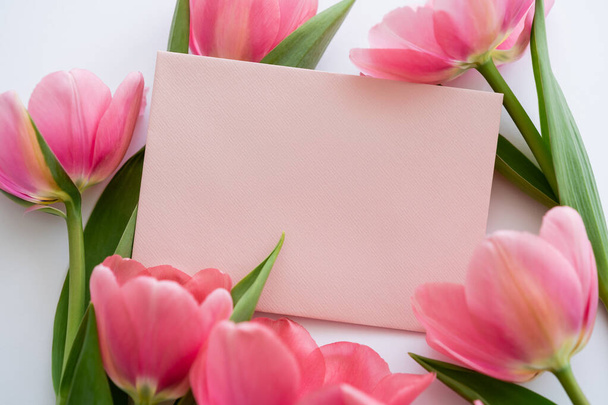 close up of pink tulips near pastel envelope on white - Photo, Image