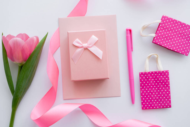 top view ajándékdoboz borítékon közel rózsaszín tulipán és bevásárló táskák fehér - Fotó, kép