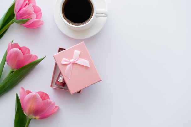 vista superior de la taza de café cerca de la caja de regalo y tulipanes rosados en blanco  - Foto, Imagen