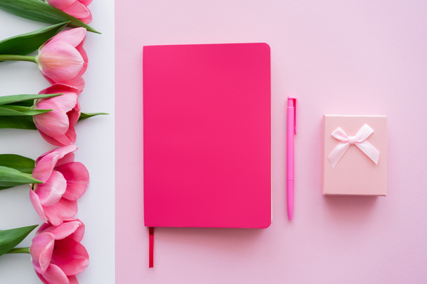 ylhäältä näkymä lahjapakkaukseen, kirkas muistikirja ja kynä lähellä tulppaanit valkoinen ja vaaleanpunainen - Valokuva, kuva