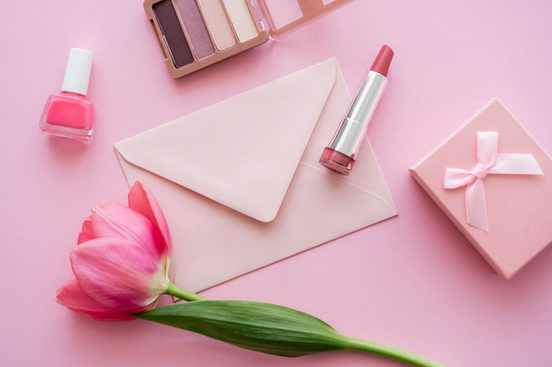 top view of blooming tulip near decorative cosmetics, envelope and gift box on pink - Fotografie, Obrázek