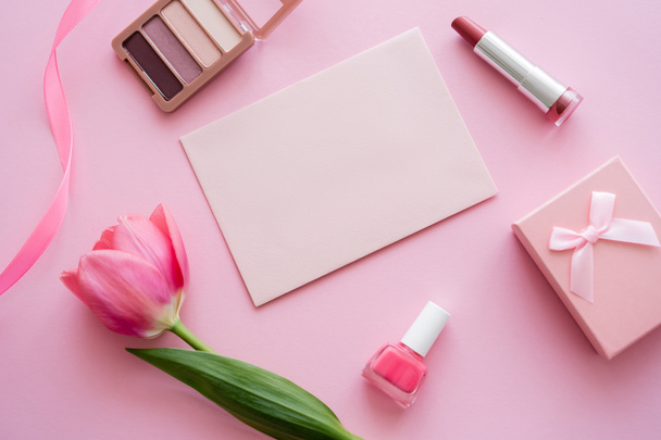top view of tulip near decorative cosmetics, envelope and gift box on pink - 写真・画像