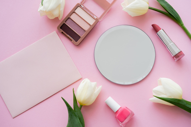 top view of white tulips near mirror, envelope and decorative cosmetics on pink - Φωτογραφία, εικόνα