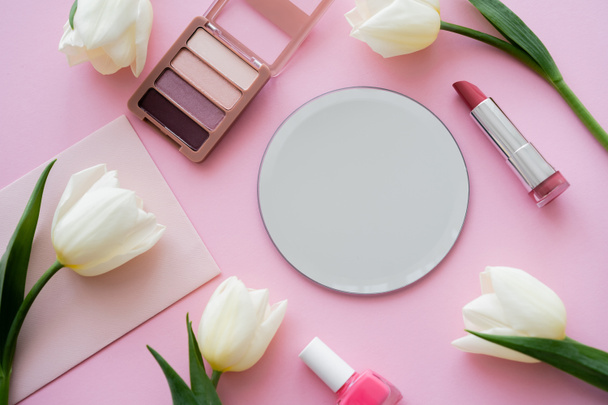 vista superior de tulipanes blancos en el sobre cerca de cosméticos decorativos en rosa - Foto, imagen