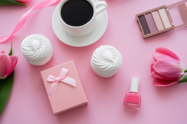 vista superior de la caja de regalo, zephyr, cosméticos decorativos y tulipanes cerca de la taza de café en rosa - Foto, Imagen