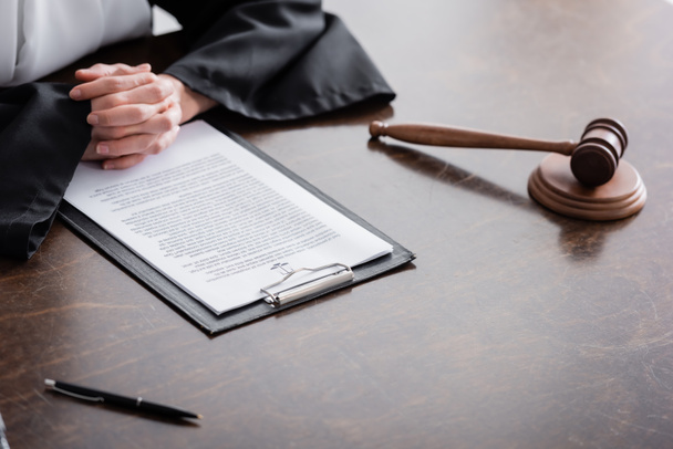 частковий погляд прокурора з затиснутими руками біля судового позову і давати на дерев'яний стіл
 - Фото, зображення