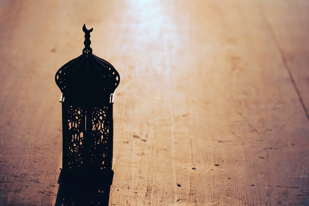 Ramadan Kareem background. Ornamental Arabic lantern on vintage wooden background in the sunset - Foto, immagini
