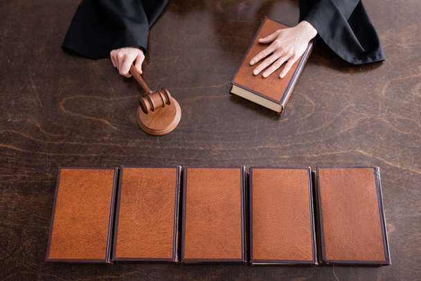 top view of cropped judge holding wooden gavel near collection of books - Foto, afbeelding