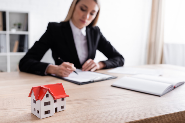 selective focus of house model and blurred notary signing contract on blurred background - Фото, изображение