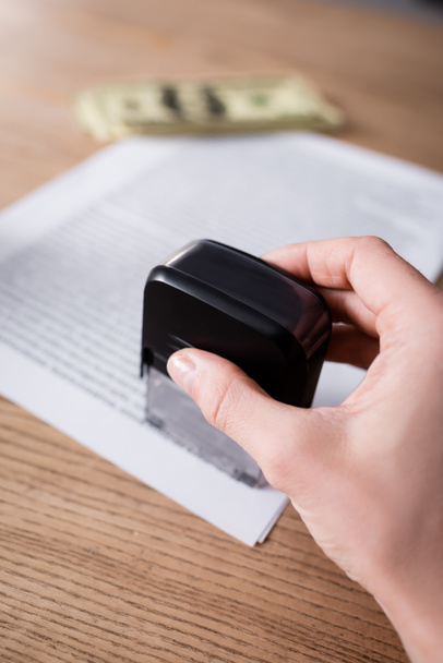 cropped view of notary with stamper near blurred contract and money - 写真・画像