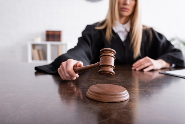 cropped view of judge holding wooden gavel on blurred background - Φωτογραφία, εικόνα