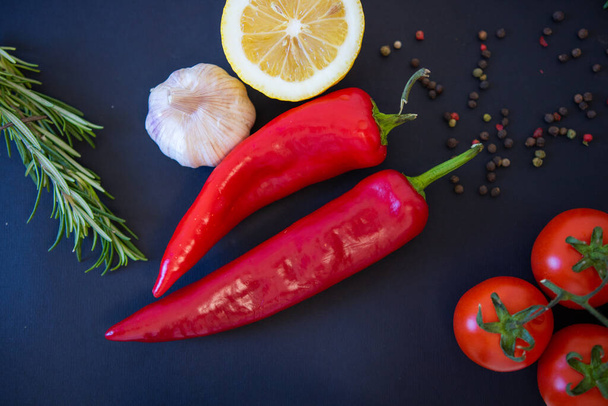黒を背景に赤野菜。ピーマンとトマト、ニンニク - 写真・画像