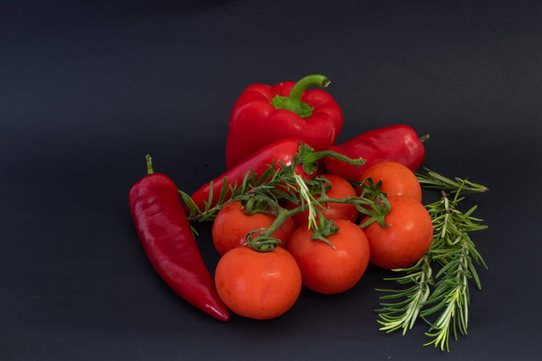 Red vegetables on a black background. Peppers and tomatoes, garlic - Fotoğraf, Görsel