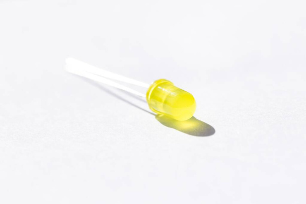 A studio portrait of a single yellow colored LED or color Light Emitting Diode lying on a white background, ready to be used in some kind of electronics PCB or circuit or print board. - Zdjęcie, obraz