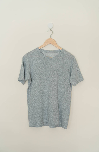 grey t-shirt hanging with wood hanger on wall - 写真・画像