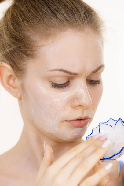 Young woman applying cream cosmetic, mask moisturizing to her face. Beauty treatment. Skincare. - Фото, зображення