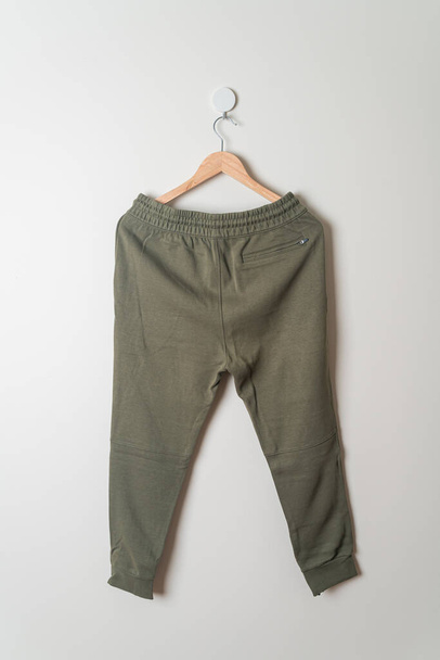 sweatpants or jogger pants hanging with wood hanger on wall - Φωτογραφία, εικόνα