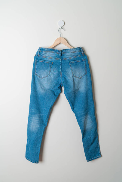 jeans trousers hanging with wood hanger on wall - Foto, Bild