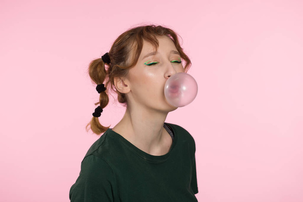 Burbuja de chicle. Joven adolescente soplando goma de mascar rosa. Chica soplando burbuja grande aislado color rosa fondo. - Foto, Imagen